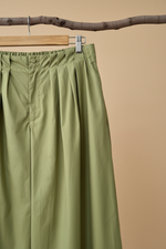 Load image in the gallery viewer,Calças verde detalhe cintura com fundo bege estúdio
