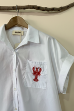 Load image in the gallery viewer,Camisa lagosta detalhe — fundo estúdio bege
