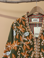 Carregar imagem no visualizador da galeria, Casaco bordado verde com fundo de estúdio bege - detalhe decote
