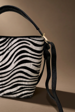 Load image in the gallery viewer,Detalhe do pêlo zebra e fivela dourada, fundo castanho quente
