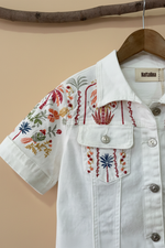 Carica l'immagine nel visualizzatore della galleria,Embroidered white denim jacket detail view studio background
