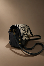 Load image in the gallery viewer,Mala zebra em vista lateral com rebites em latão, fundo castanho quente
