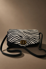 Load image in the gallery viewer,Mala zebra pequena vista frontal com alça enrolada, fundo castanho quente
